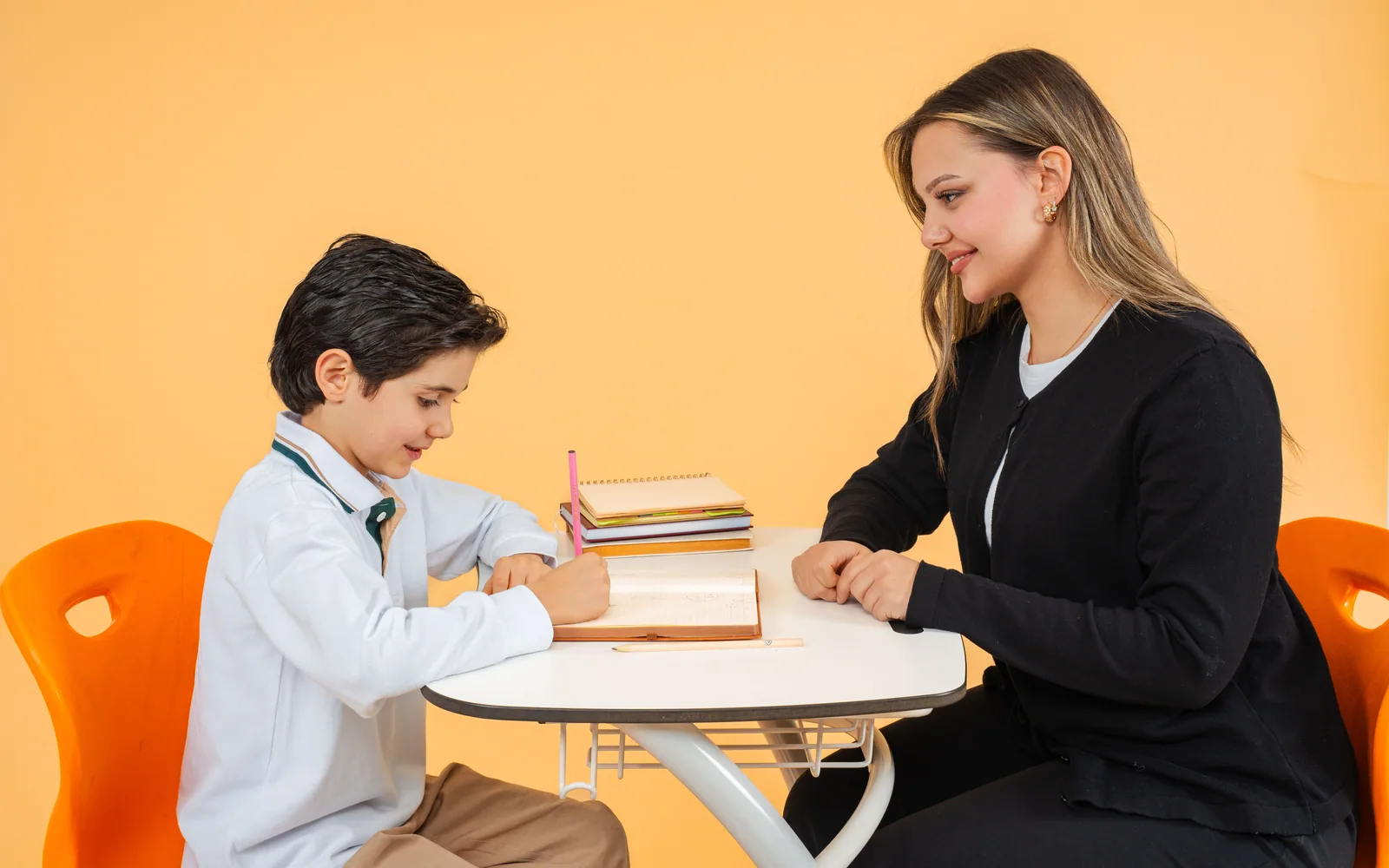 A student writing while an educator sits nearby and observes