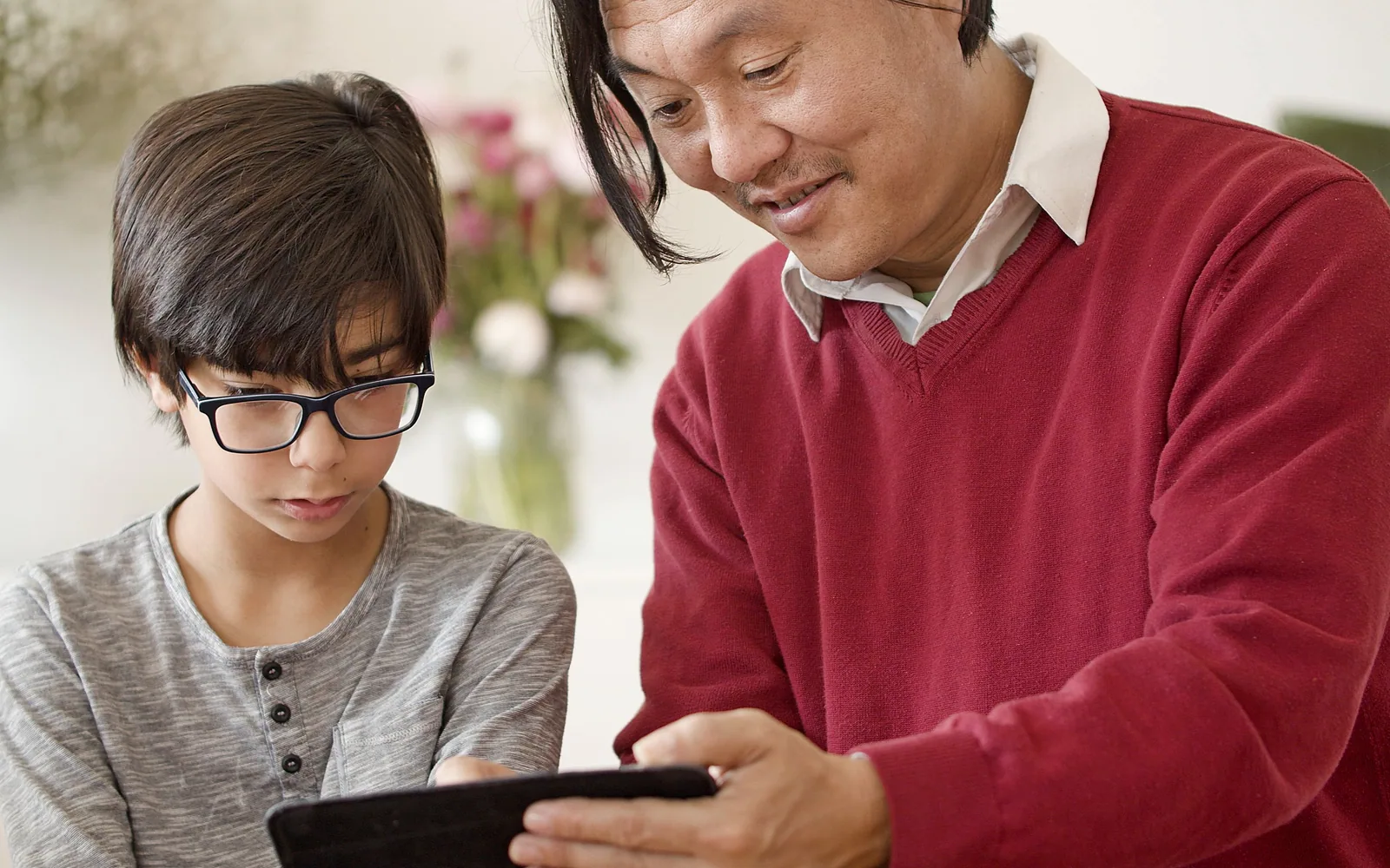 A father and child sitting together and looking at a tablet