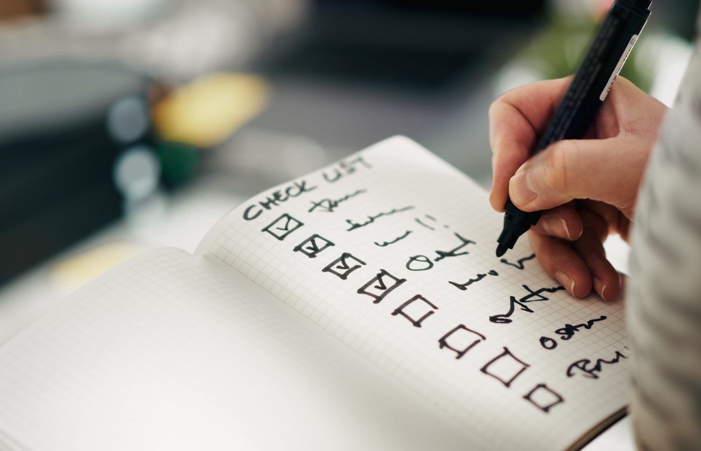 A person marking boxes on a handwritten checklist in a notebook