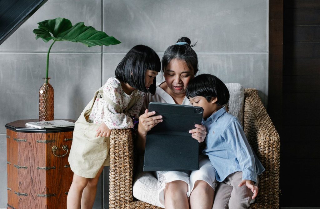 An older adult and two children looking at a tablet together at home
