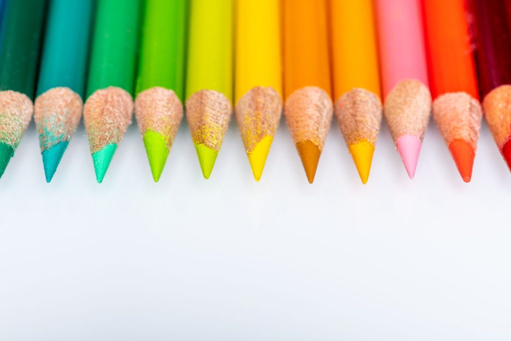 A row of sharpened coloured pencils on a white surface.